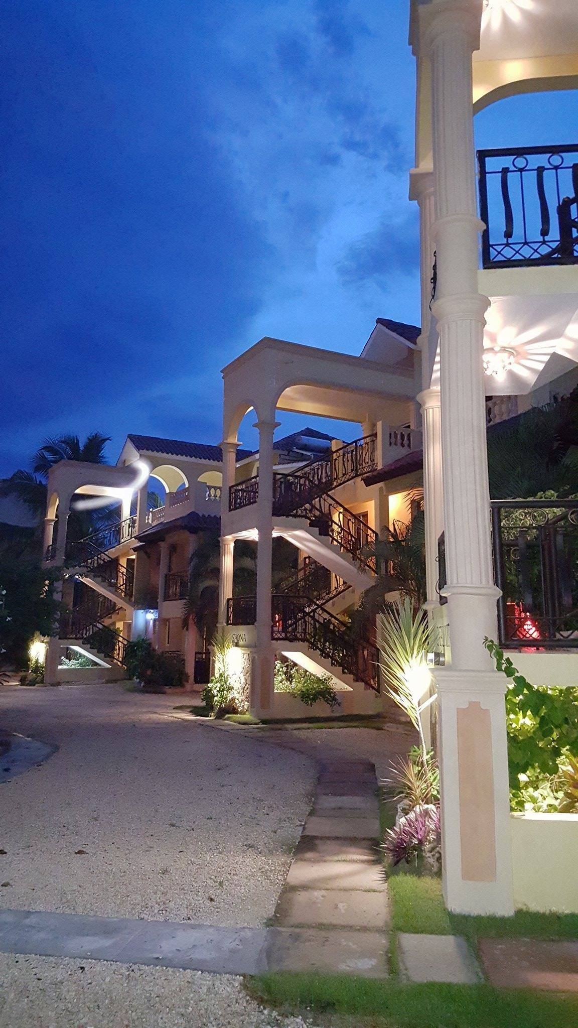 The apartment buildings lit up at night, with outdoor staircases and stone columns