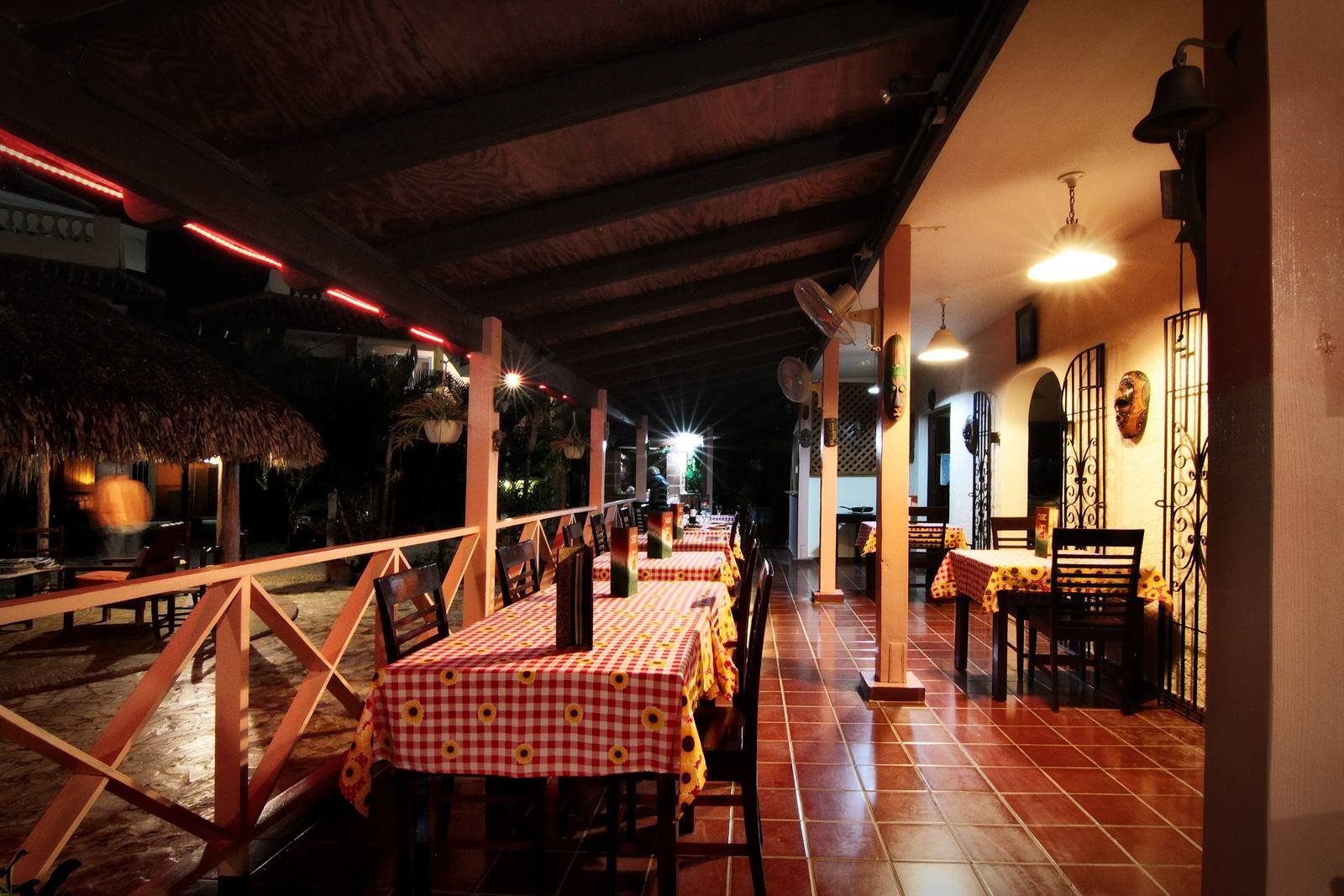 Covered breakfast terrace with checked tablecloths and wooden chairs